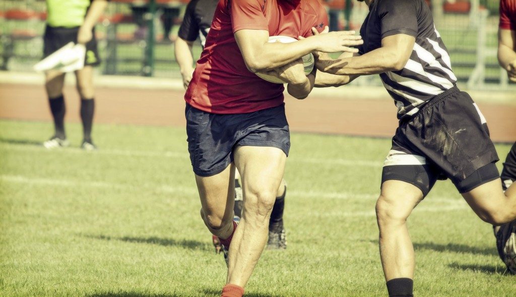 Men playing rugby in the field